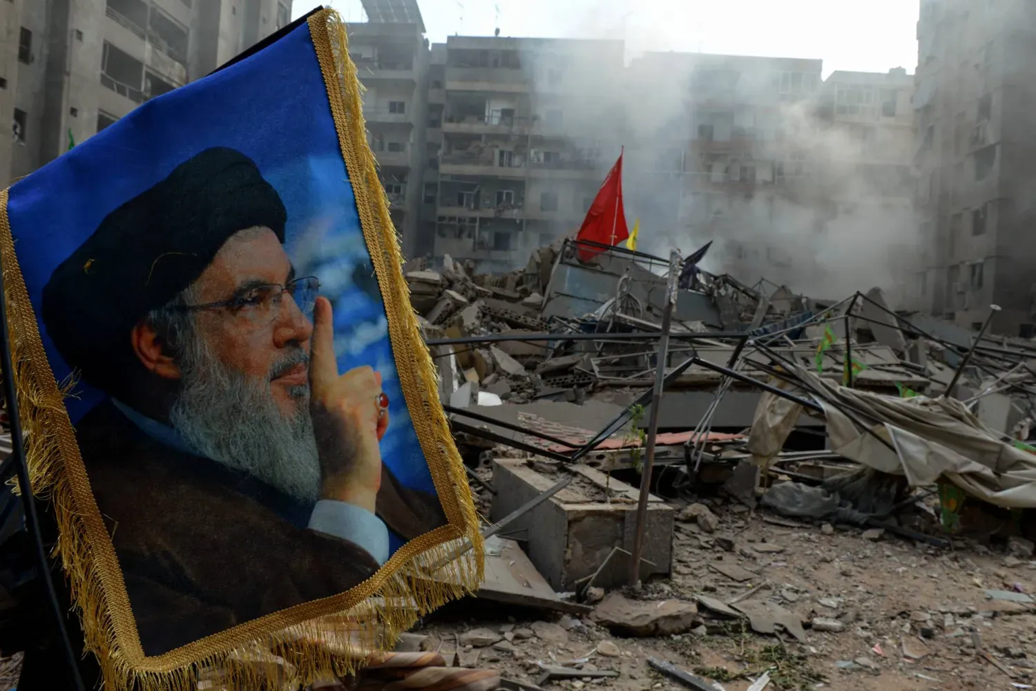 Hasan Nasrallah'ın, Beyrut'un güney banliyölerinde İsrail uçaklarının yıktığı bir binanın enkazı önündeki fotoğrafı (DPA)