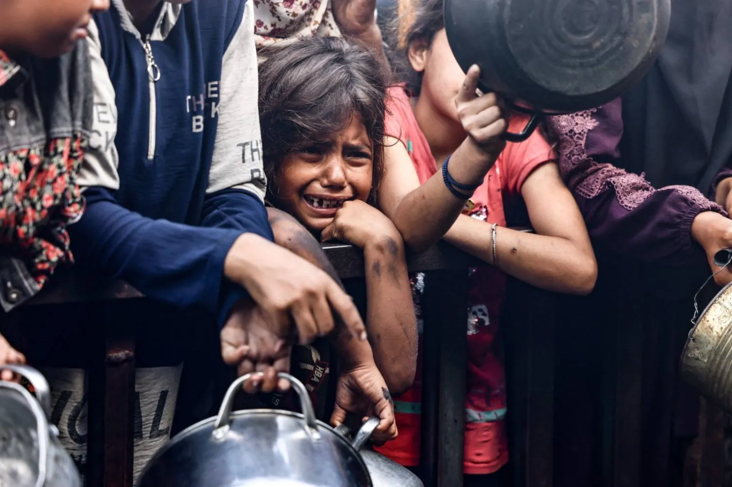 طفلة فلسطينية تبكي وسط نازحين فلسطينيين يشقّون طريقهم بشِقّ الأنفس أمام مطبخ مجتمعي بخان يونس (أ.ف.ب)