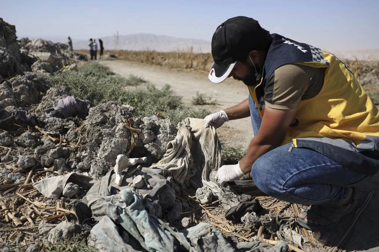  A Syrian Civil Defense worker checks clothes found along with human remains in Otaiba, on the outskirts of Damascus, Syria, Friday, Sept. 19, 2025. (AP)