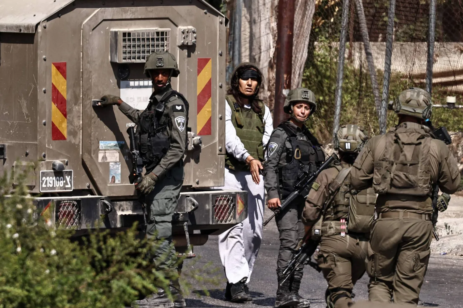 جنود إسرائيليون يعتقلون امرأة فلسطينية خلال اقتحام مدينة رام الله في الضفة الغربية (أ.ف.ب)