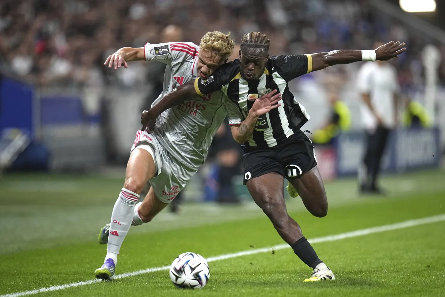 آدم كارابيك لاعب ليون يتنافس على الكرة مع جاك إيكومي من أنجيه (أ.ب)