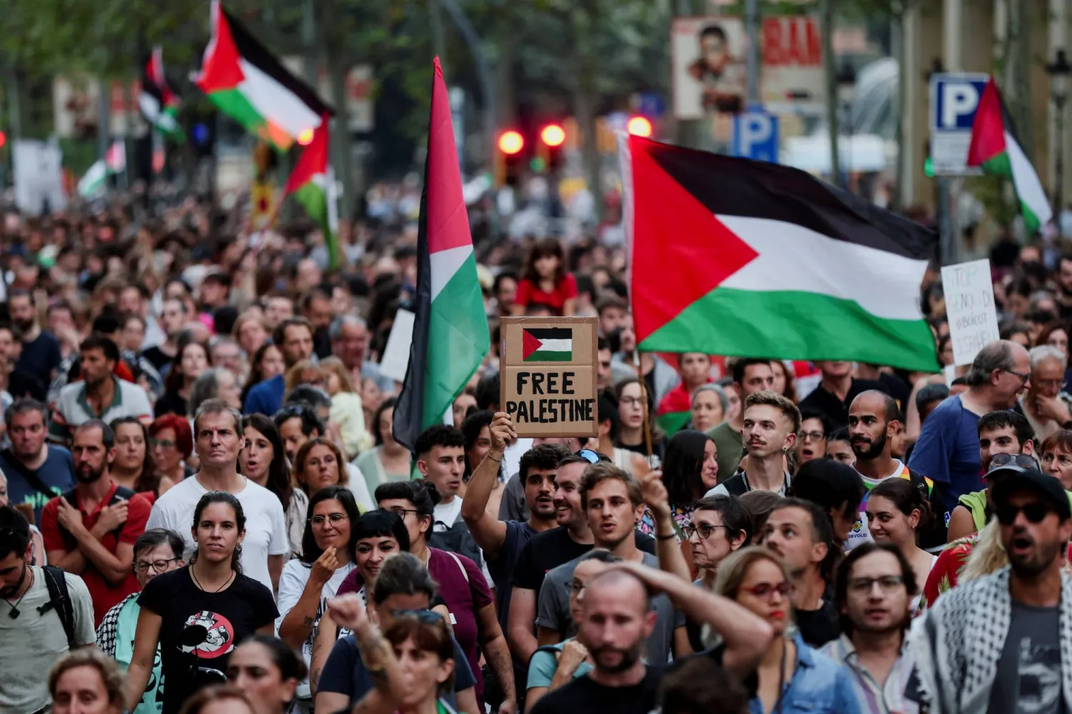 متظاهرون يرفعون الأعلام الفلسطينية في إسبانيا (رويترز)