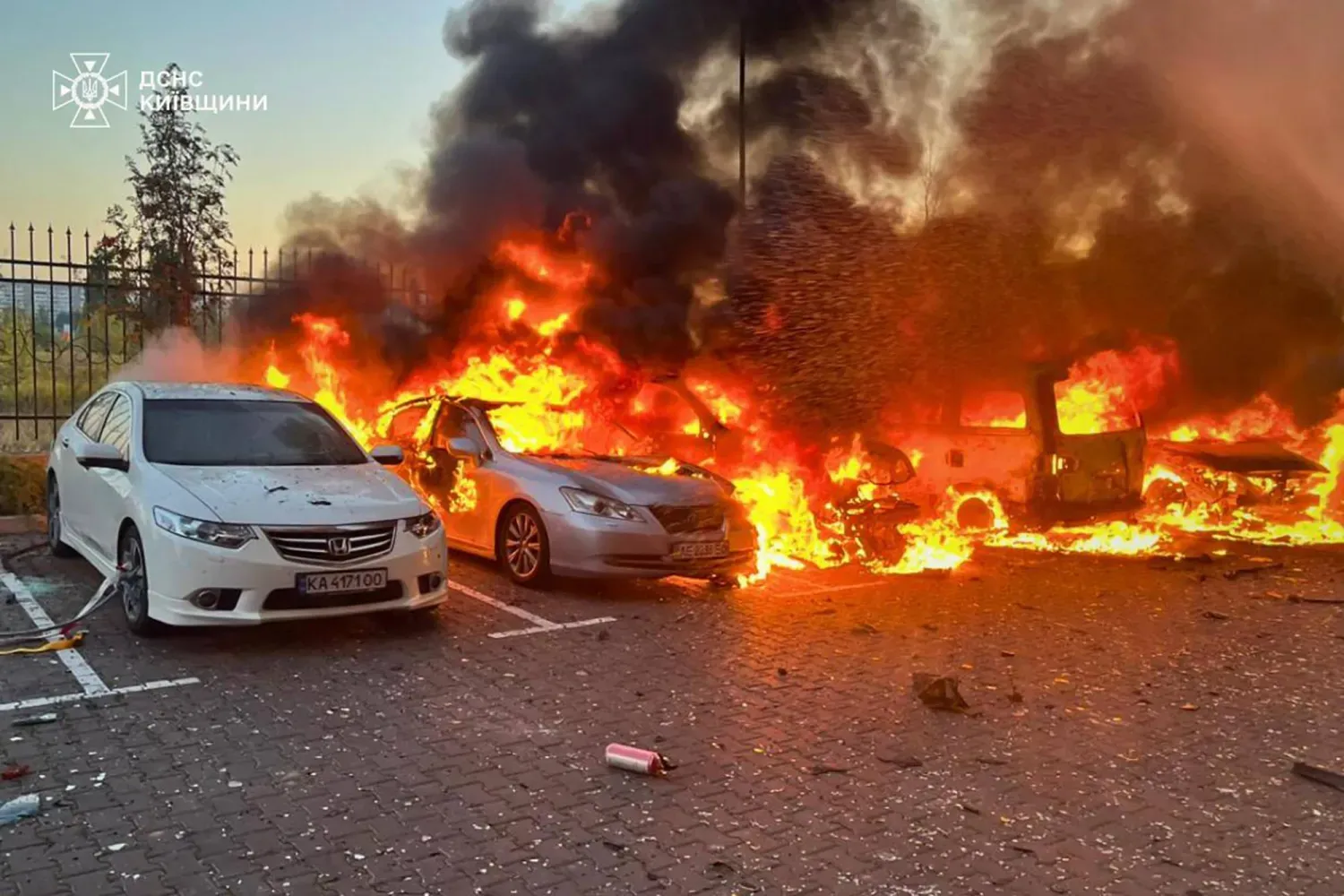 Rusya'nın Ukrayna'yı işgali sırasında Kiev bölgesinde açıklanmayan bir noktaya düzenlenen hava saldırısının ardından bir otoparkta yanan arabalar (AFP)
