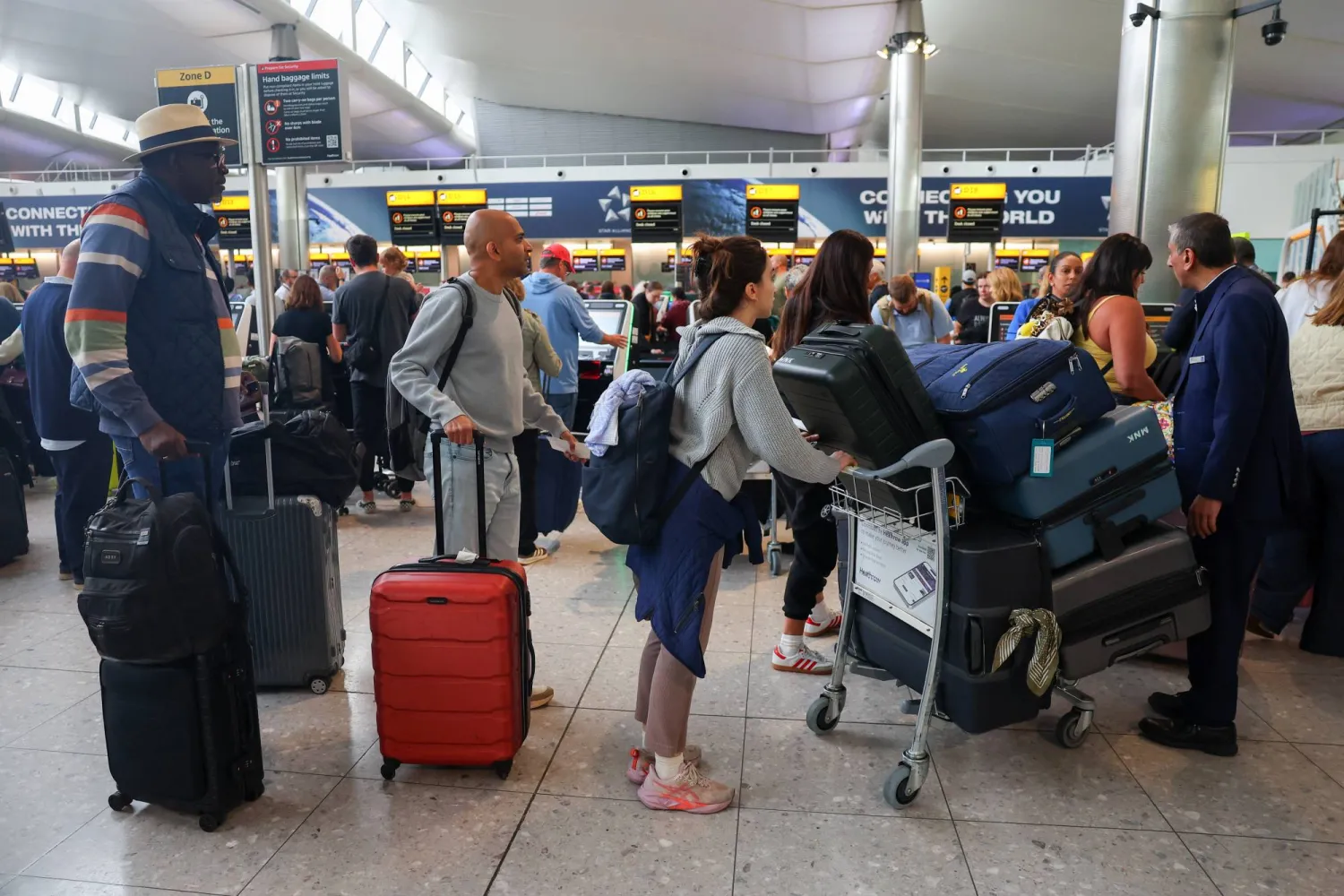 مسافرون ينتظرون في مبنى الركاب رقم 2 بمطار هيثرو بعد تعطل أنظمة تسجيل الوصول جرّاء هجوم إلكتروني أثر على مطارات أوروبية كبرى (رويترز)