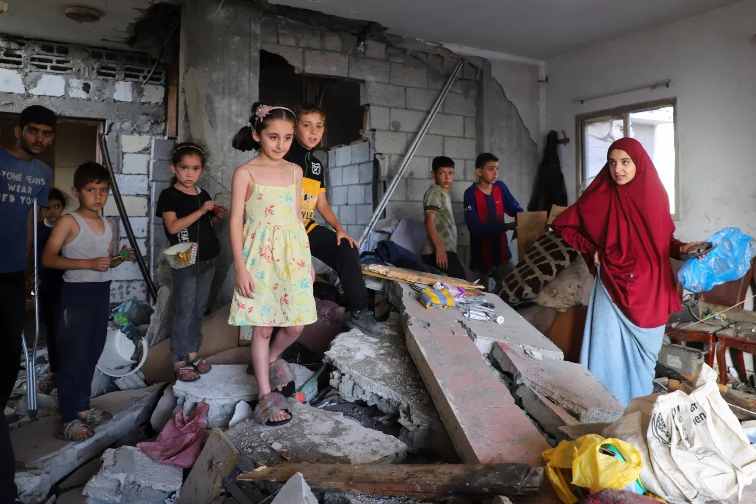Filistinli çocuklar, dün gece İsrail bombardımanının hedefi olan Gazze şehrindeki Haddad ailesinin evinden geriye kalanları inceliyorlar. (Reuters)