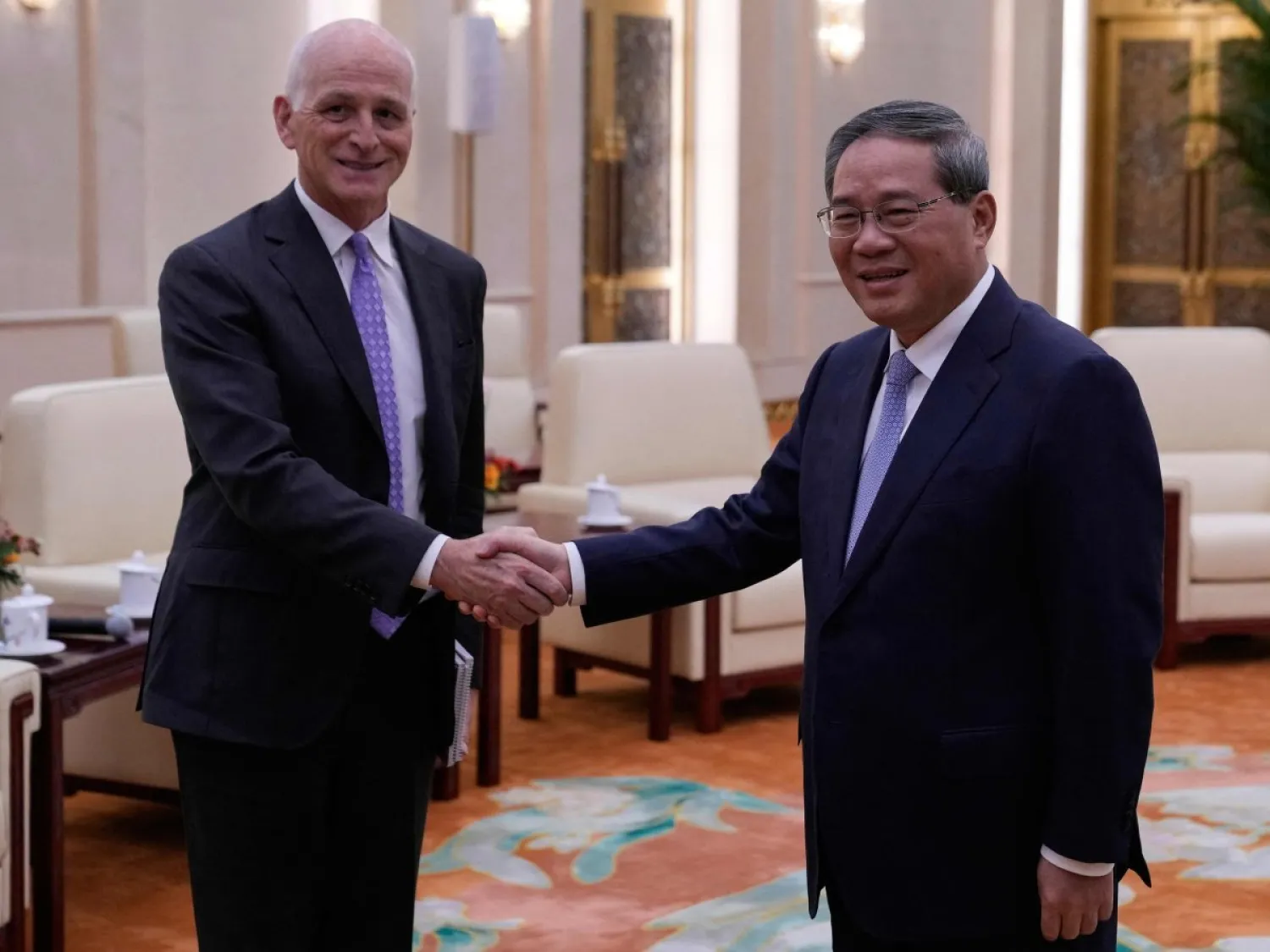 النائب الديمقراطي وعضو لجنة القوات المسلحة بمجلس النواب الأميركي آدم سميث (يسار) يصافح رئيس مجلس الدولة الصيني لي تشيانغ خلال لقائهما في قاعة الشعب الكبرى ببكين اليوم (أ.ف.ب)