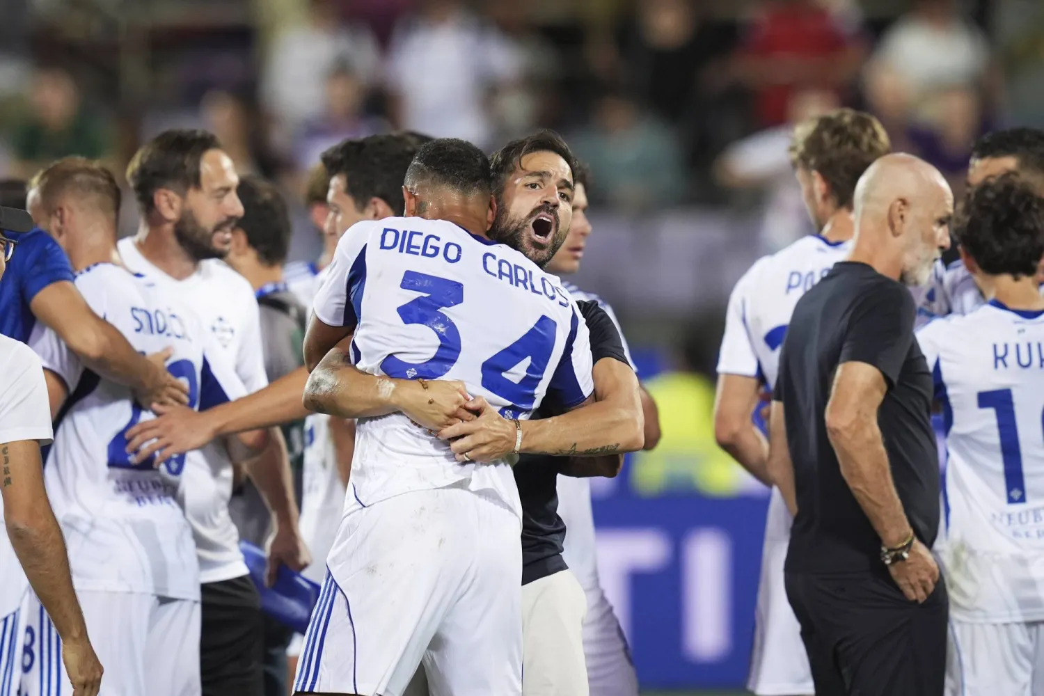 سيسك فابريغاس مدرب كومو يحتضن لاعبه دييغو كارلوس احتفالاً بالفوز العصيب على فيورنتينا (أ.ب)