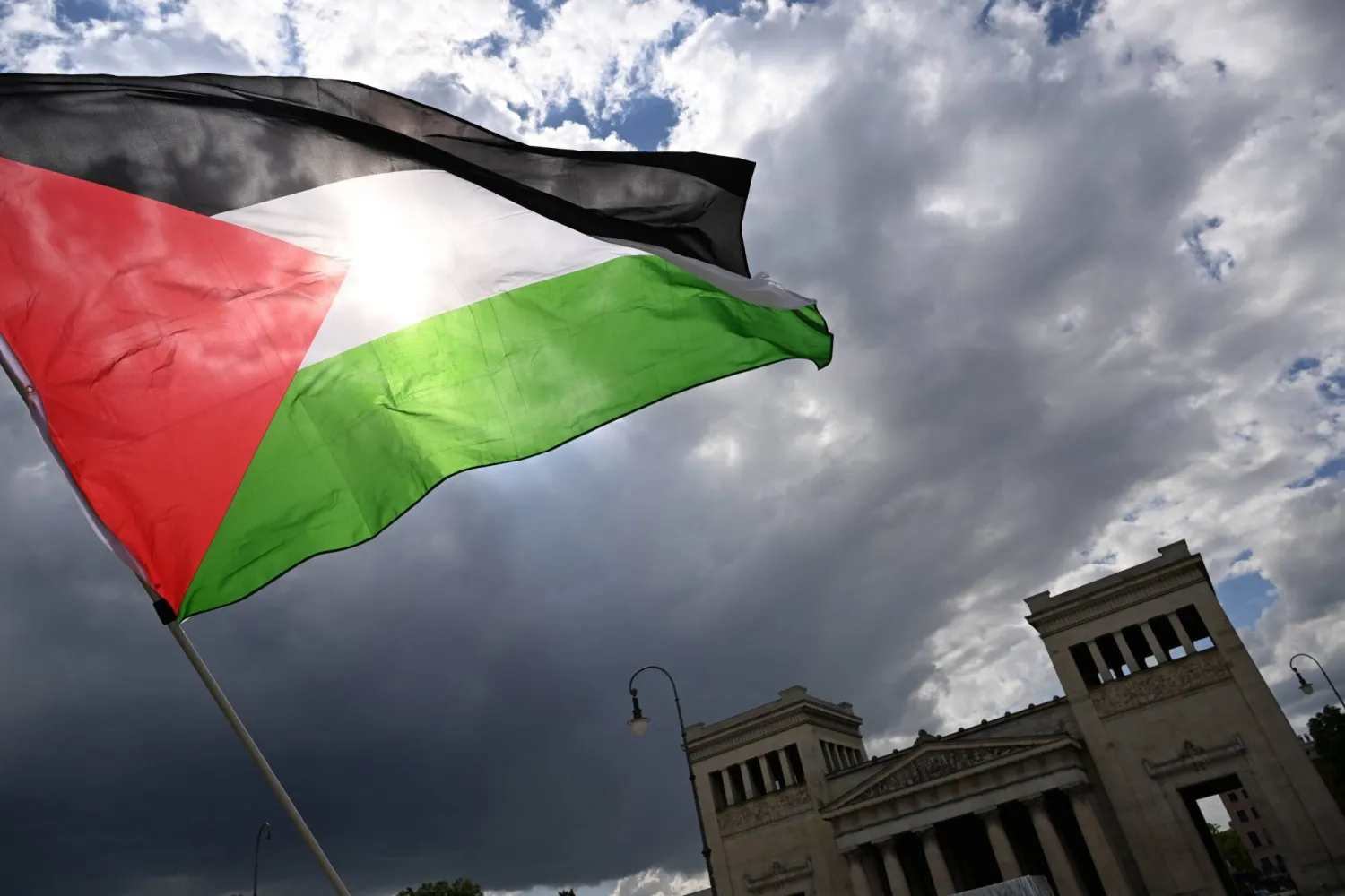 17 May 2025, Bavaria, Munich: A protester waves a Palestinian flag during a demonstration on Koenigsplatz. (dpa)