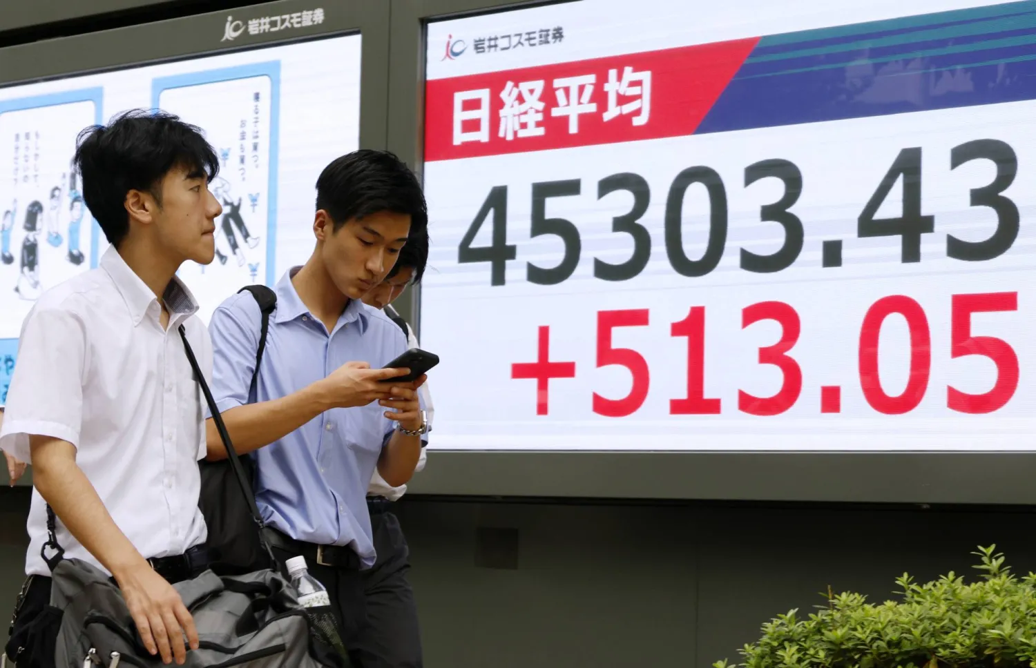 مشاة يمرون أمام لوحة تعرض حركة الأسهم بالعاصمة اليابانية طوكيو (إ.ب.أ)