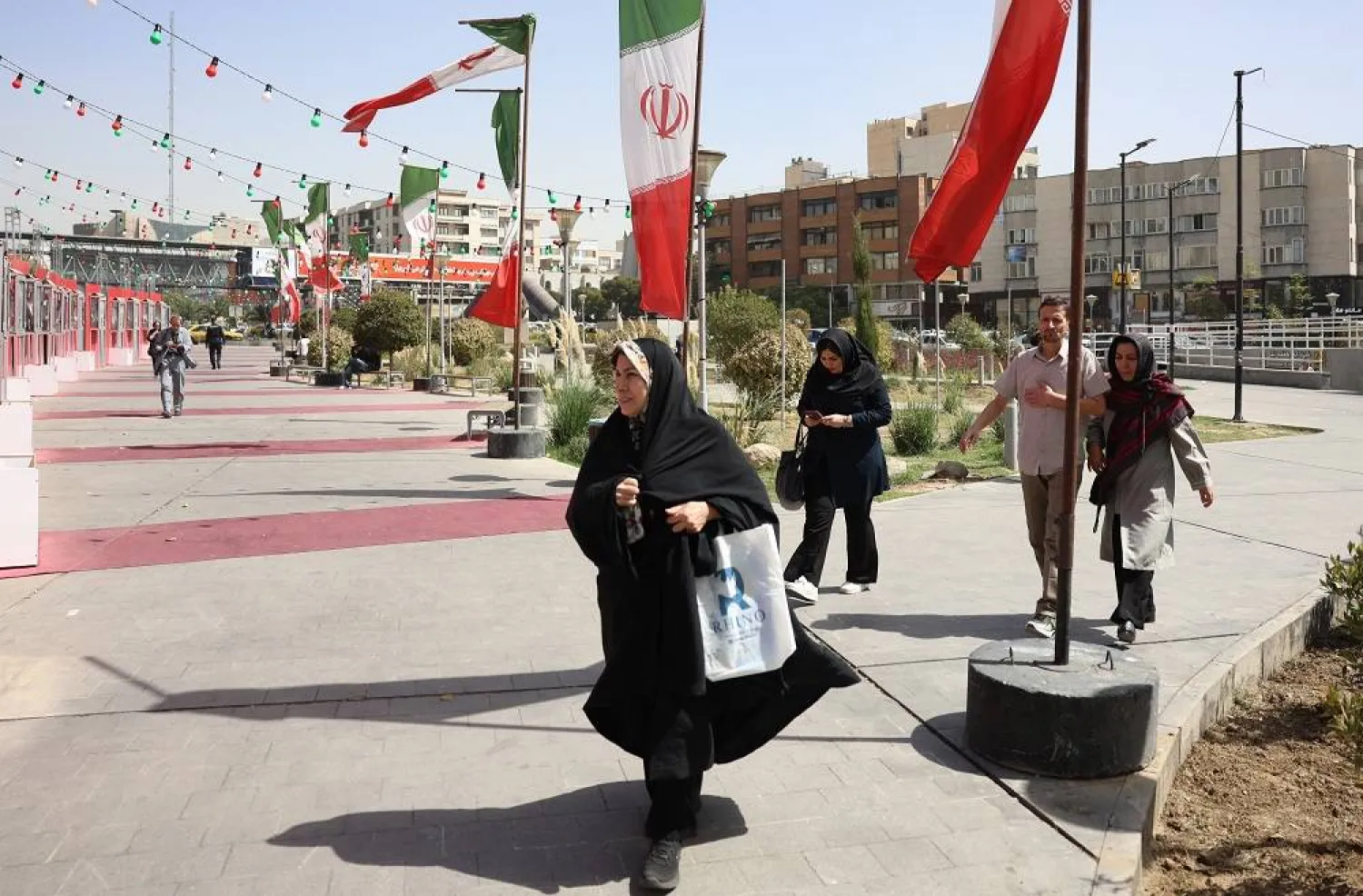 Iranians walk next to Iran's national flags in Tehran, Iran, 20 September 2025. (EPA)
