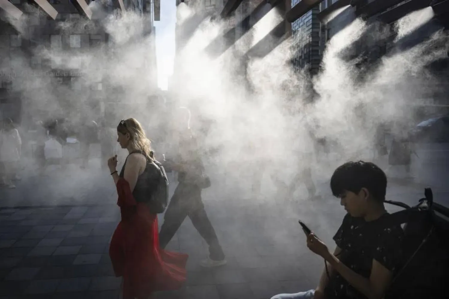 يسير الناس تحت نظام رذاذ الماء للتبريد في يوم حار في طوكيو (غيتي)