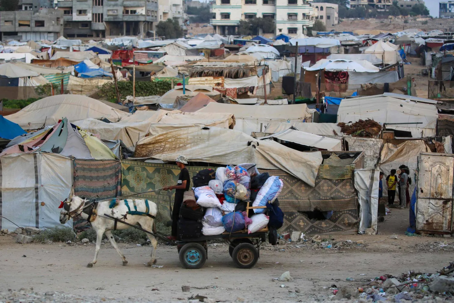 A displaced Palestinian man drives his cart past shelters at the Bureij camp for refugees in the central Gaza Strip on September 22, 2025. (Photo by Eyad BABA / AFP)