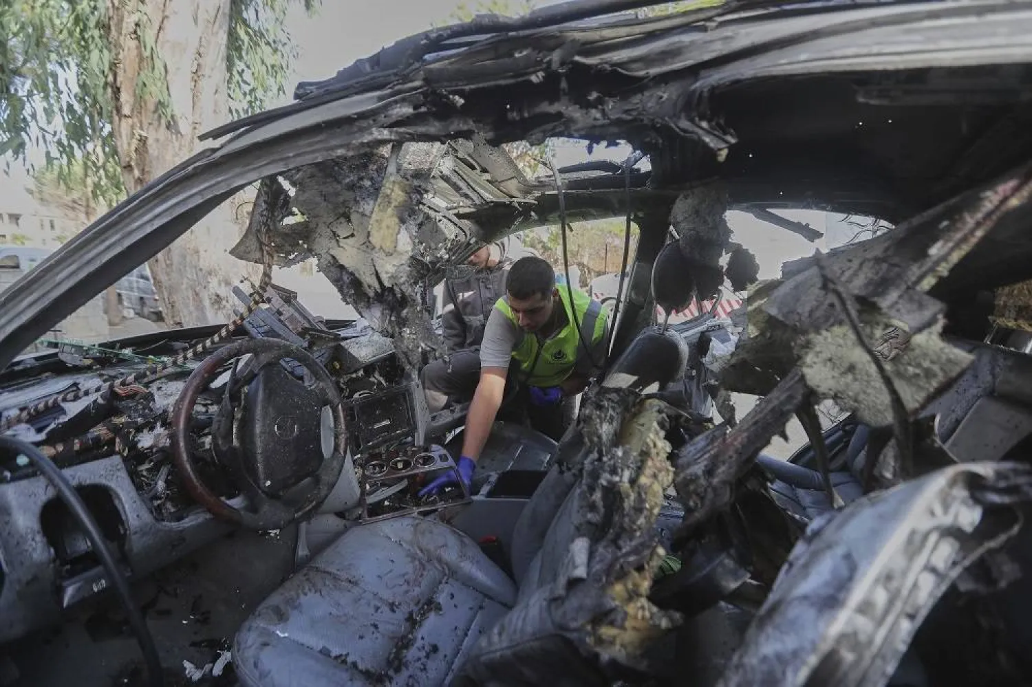A civil defense worker inspects a damaged car hit the previous day in an Israeli drone strike that killed four members of the same family in Bint Jbeil, southern Lebanon, Monday, Sept. 22, 2025. (AP)