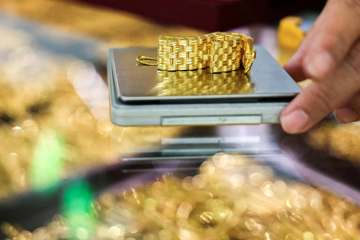 A gold seller weighs a gold watch bracelet inside a gold shop, on the day that gold surges to set a fresh record high, in Bangkok, Thailand, September 22, 2025. REUTERS/Chalinee Thirasupa  