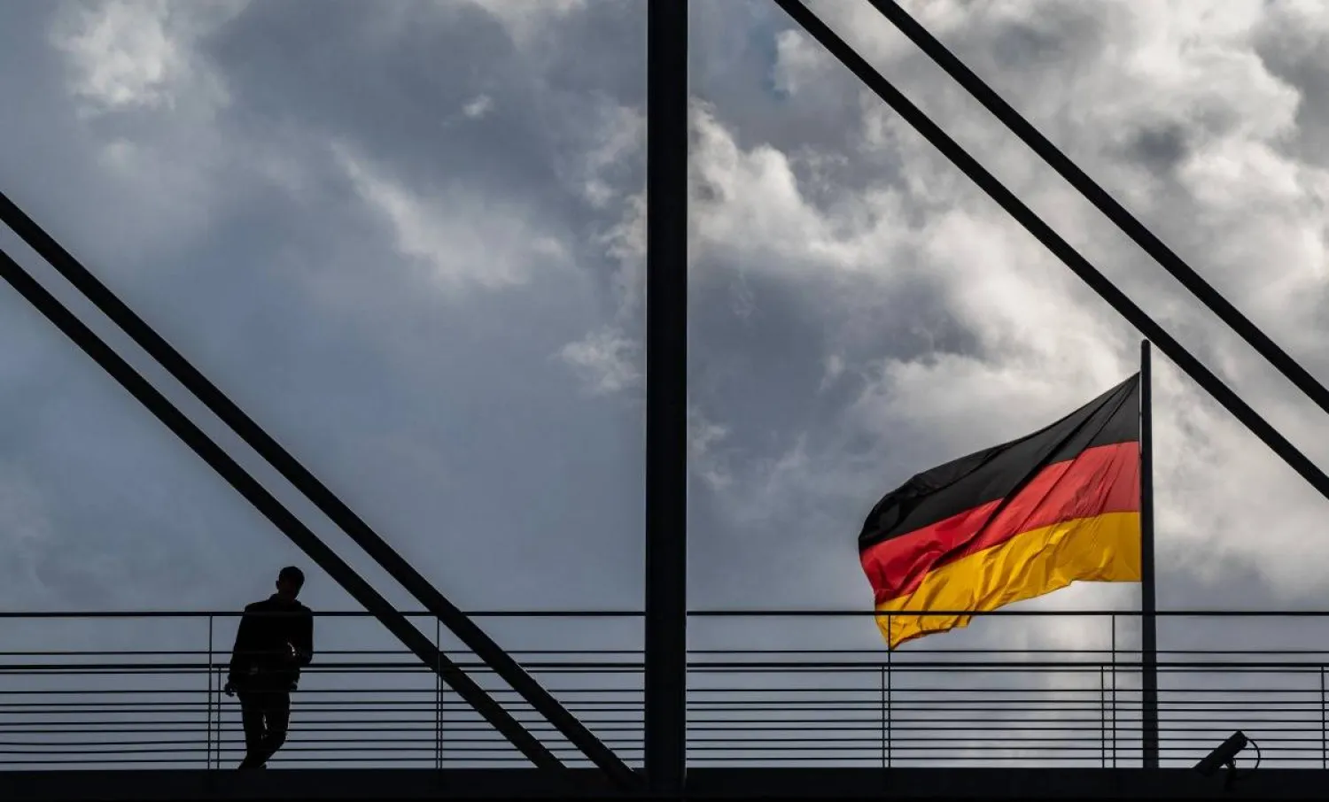 A man pauses on a pedestrian bridge as a German flag flies over the Reichstag building in Berlin on October 23, 2024. (AFP)