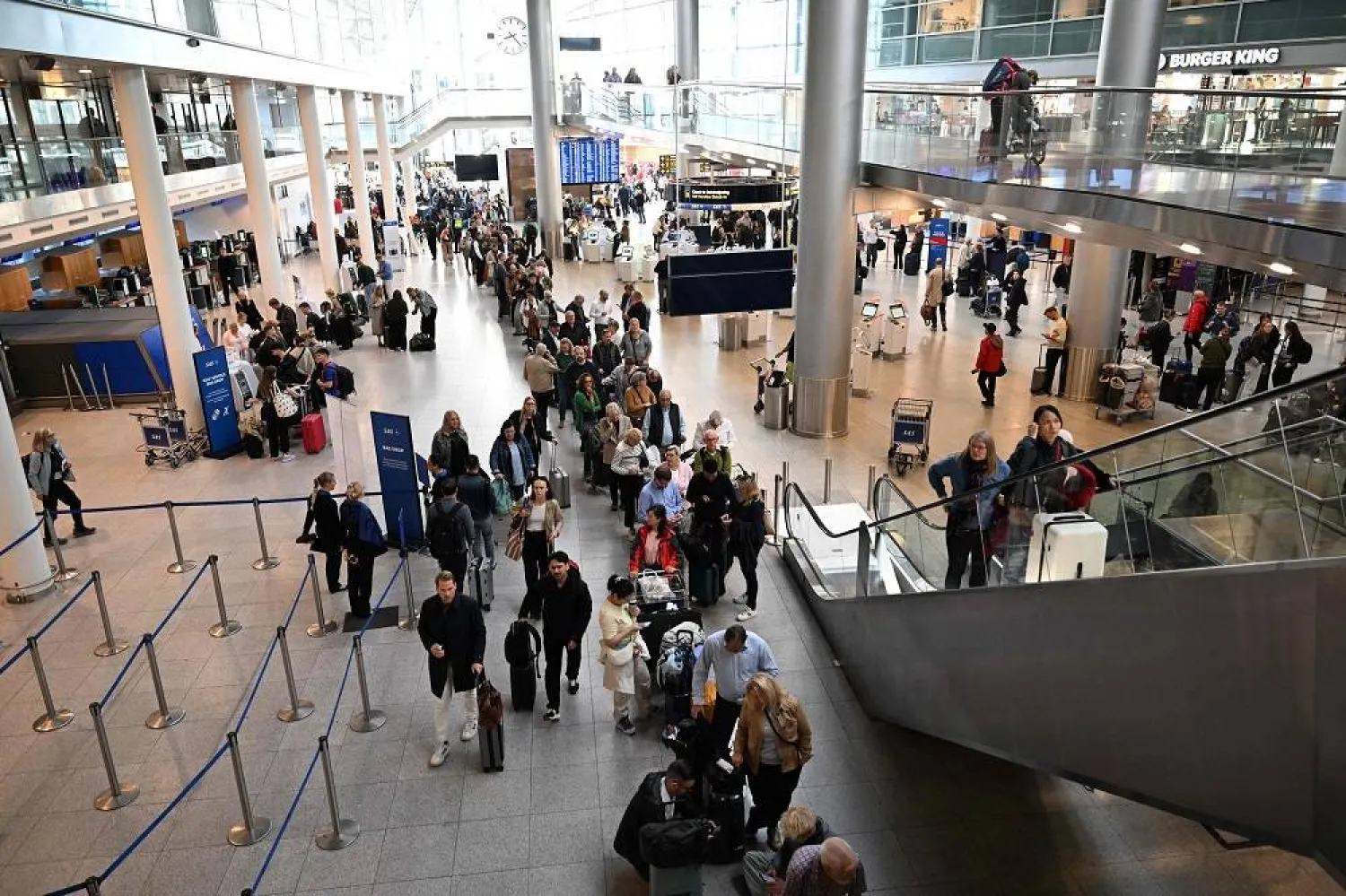 Passengers stand in a queue to get new tickets at the service point of the Copenhagen Airport in Copenhagen, Denmark, on September 23, 2025. (AFP)
