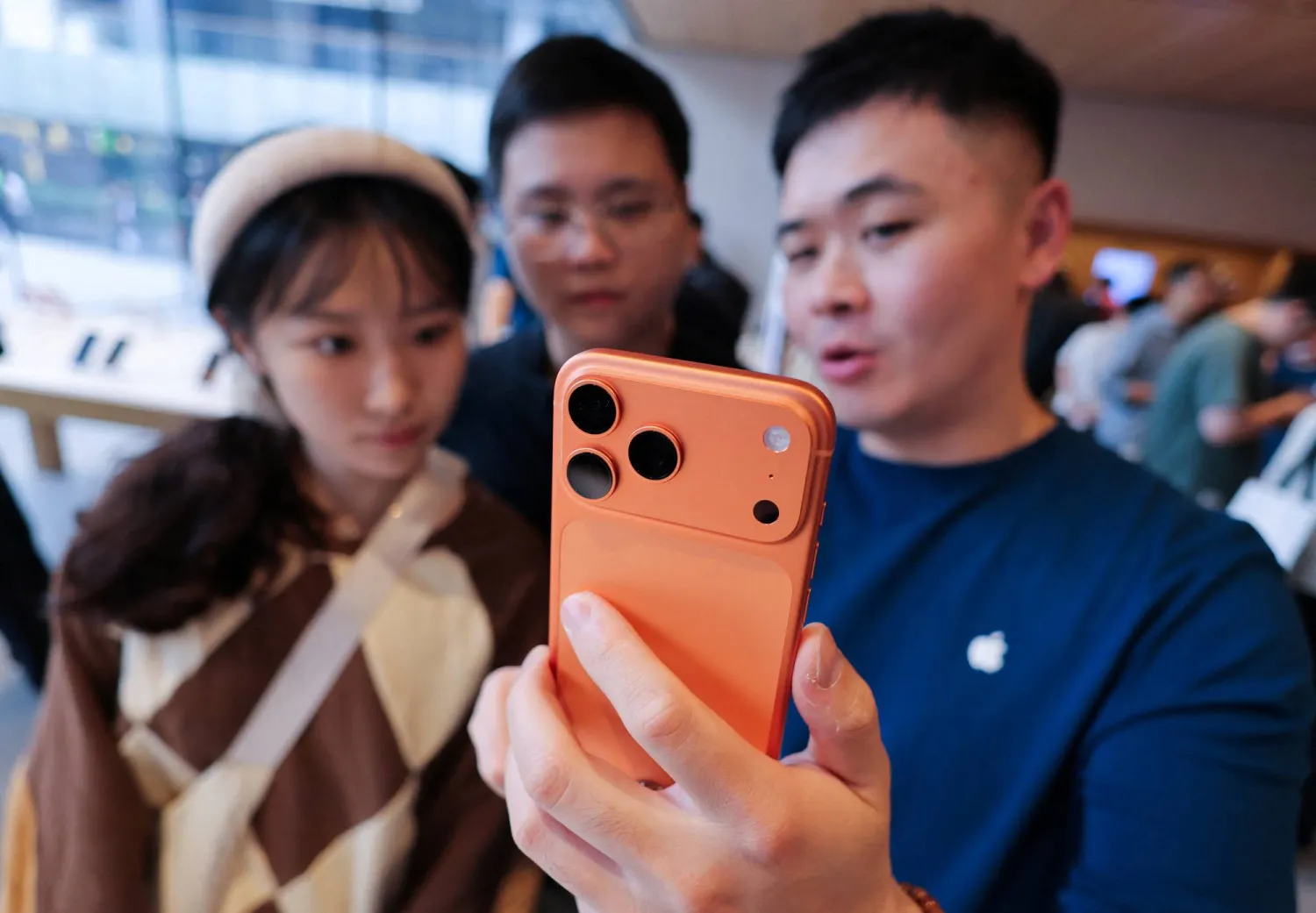 موظف يعرض هاتف «آيفون» الجديد للمتسوقين في بكين (رويترز)