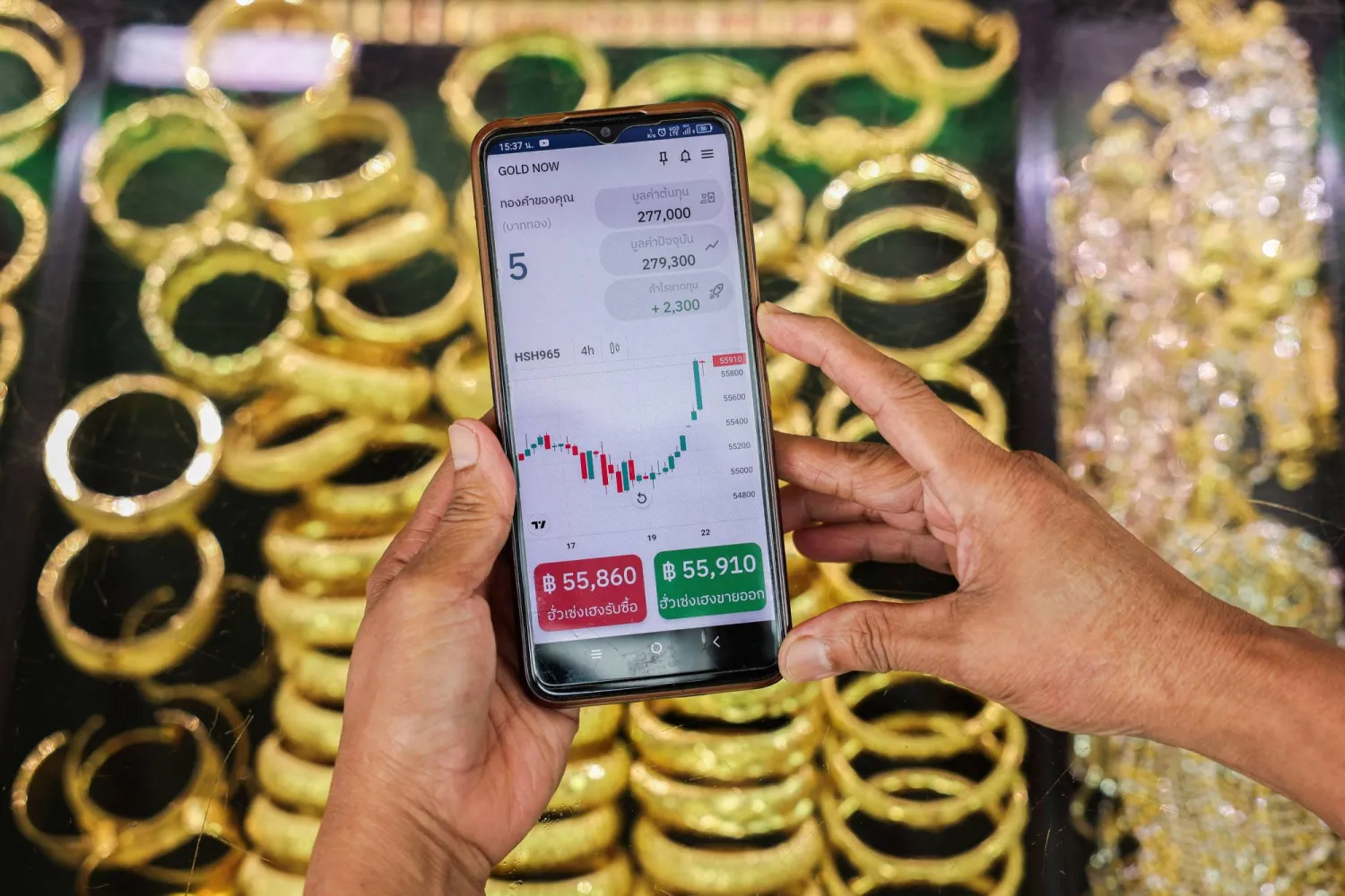 امرأة تستخدم «غولد ناو» -وهو تطبيق لتجارة الذهب طوَّره تاجر ذهب تايلاندي- على هاتفها المحمول للتحقق من سعر الذهب (رويترز)