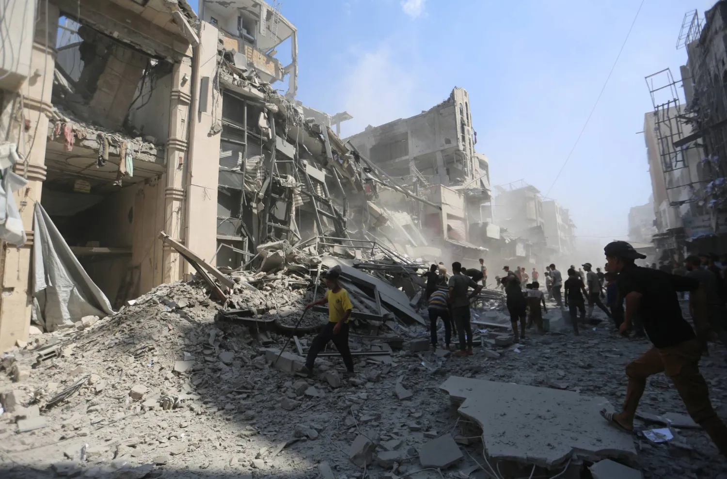 فلسطينيون يسيرون وسط أنقاض حيهم المدمر بعد غارة جوية إسرائيلية على مدينة غزة (د.ب.أ) 