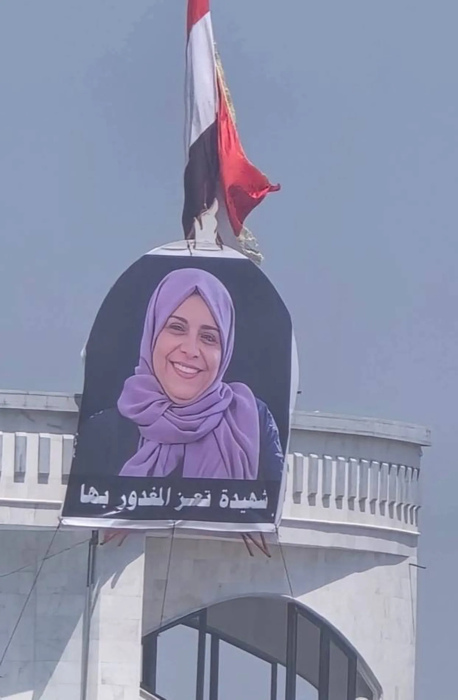 Protesters display photo of Iftihan al-Mashhari at government building (X) 