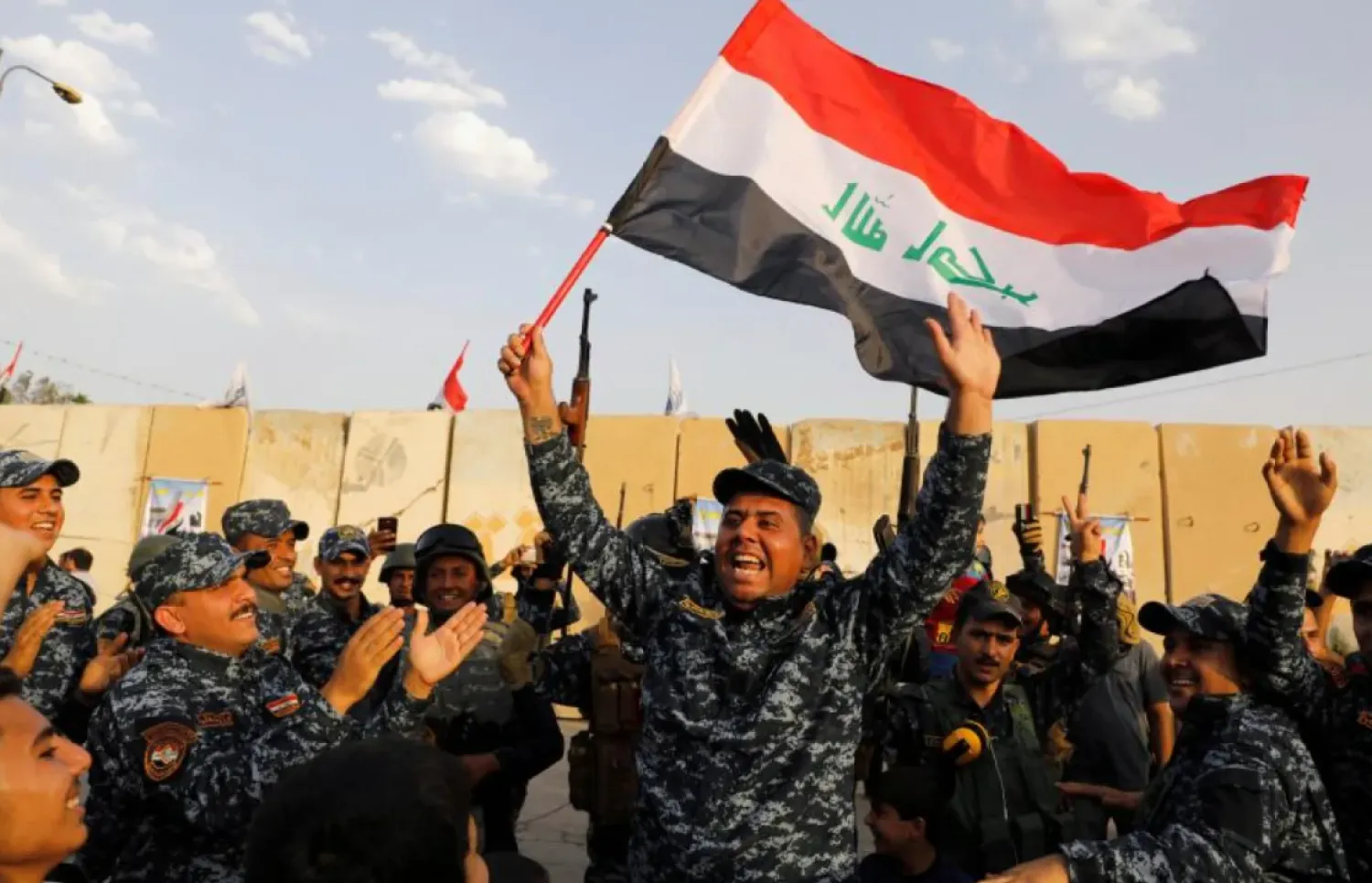 A member of Iraqi Federal Police waves an Iraqi flag as they celebrate victory of military operations against ISIS in West Mosul, Iraq July 2, 2017. (Reuters)
