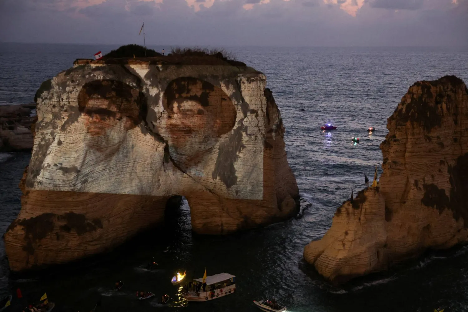 صخرة الروشة مضاءة بصورتين لحسن نصر الله وهاشم صفي الدين في ذكرى اغتيالهما أمس (رويترز)
