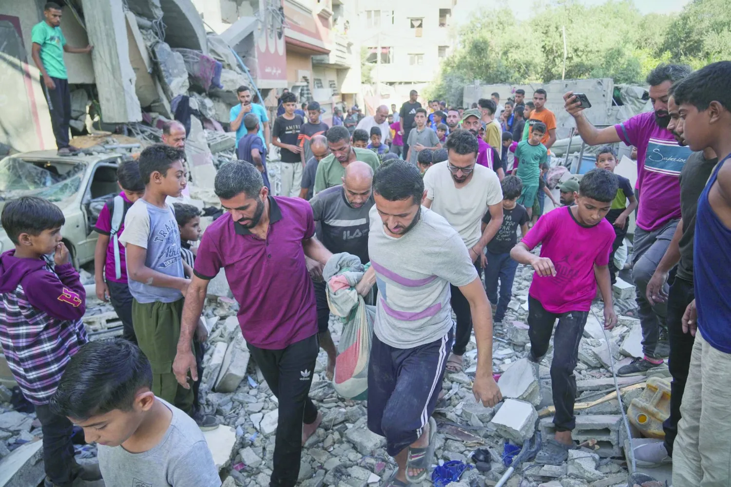 Palestinians carry the body of Hassan Nasr, 12, from the rubble of his relatives home, which was hit by an Israeli military strike in Zawaida, central Gaza Strip, Thursday, Sept. 25, 2025. (AP Photo/Abdel Kareem Hana)