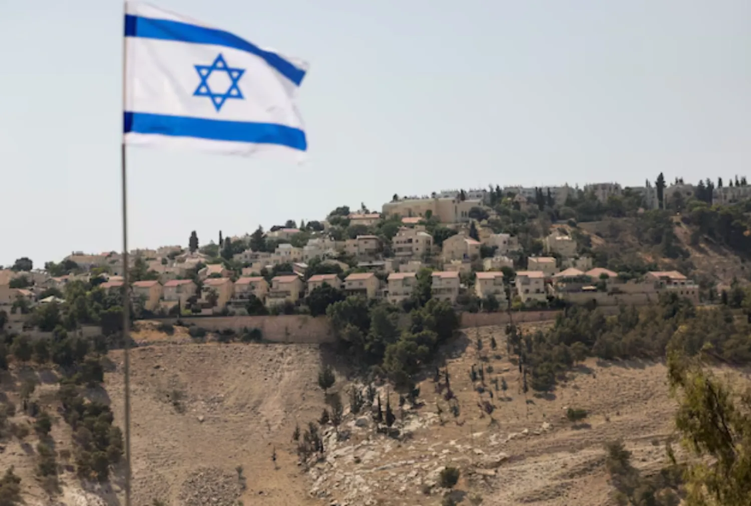 An Israeli flag flutters, as part of the Israeli settlement of Maale Adumim is visible in the background, in the Israeli-occupied West Bank, August 14, 2025. REUTERS/Ronen Zvulun/File 
