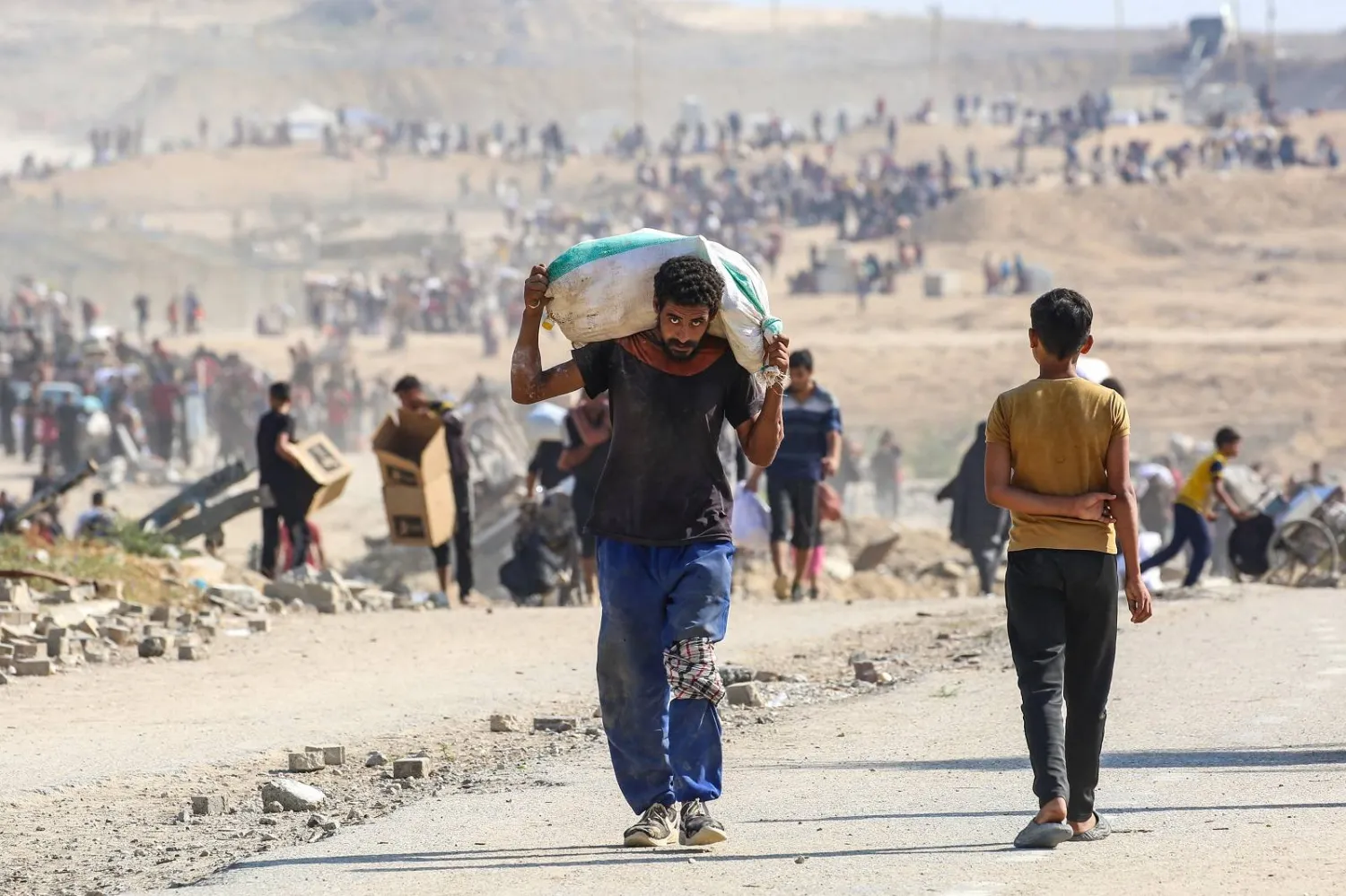 فلسطيني يسير حاملاً حقيبة مساعدات إنسانية في النصيرات وسط قطاع غزة (أ.ف.ب)