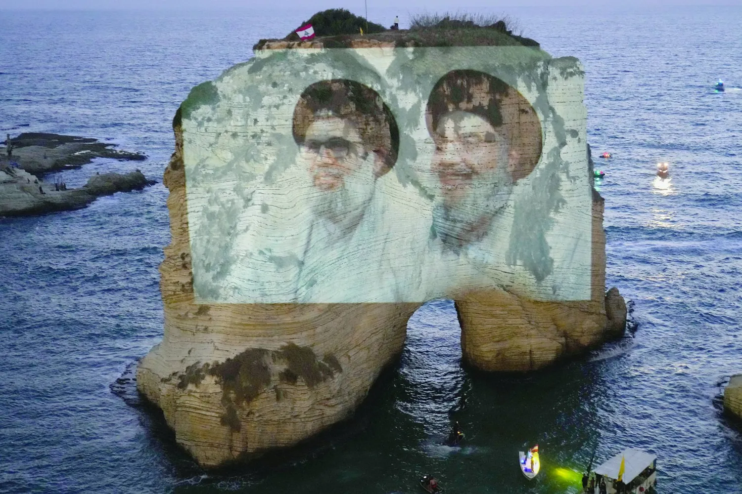 
إضاءة صخرة الروشة في بيروت بصورة تجمع الأمينين العامين السابقين لـ«حزب الله» حسن نصر الله وهاشم صفي الدين مساء الخميس (أ.ب)