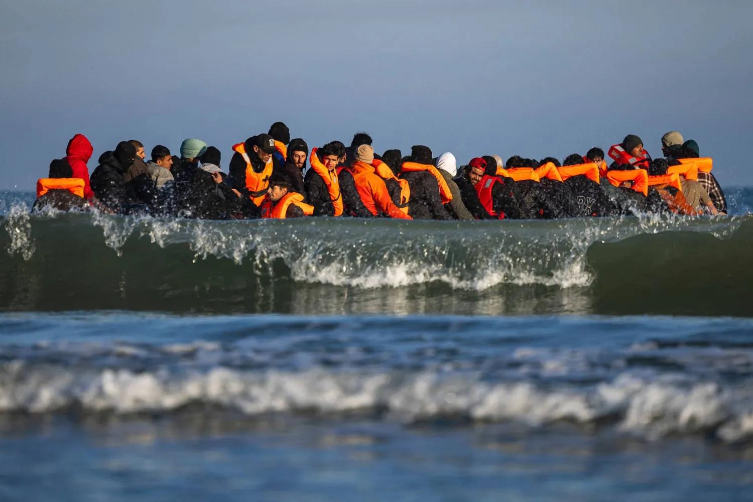 Migrants sit in a sumgglers' boat in an attempt to cross the English Channel off the beach of Gravelines, northern France on September 27, 2025. (Photo by Sameer Al-DOUMY / AFP)