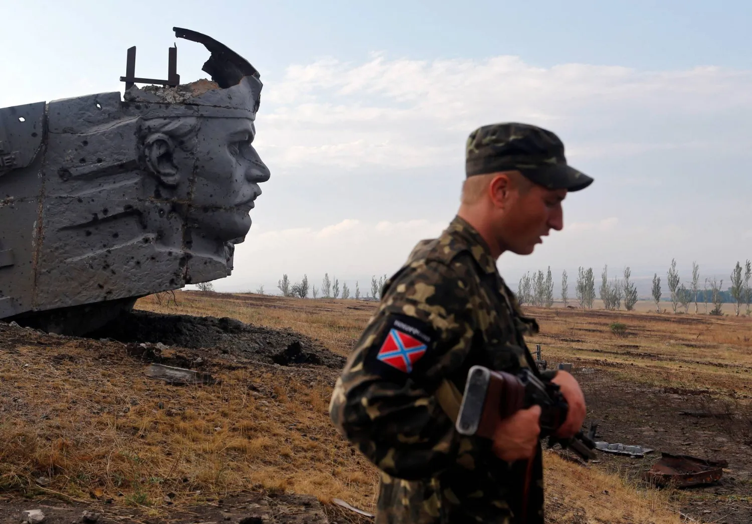 جندي موالٍ لروسيا يقف بالقرب من نصب تذكاري في شرق مدينة دونيتسك الأوكرانية (رويترز)