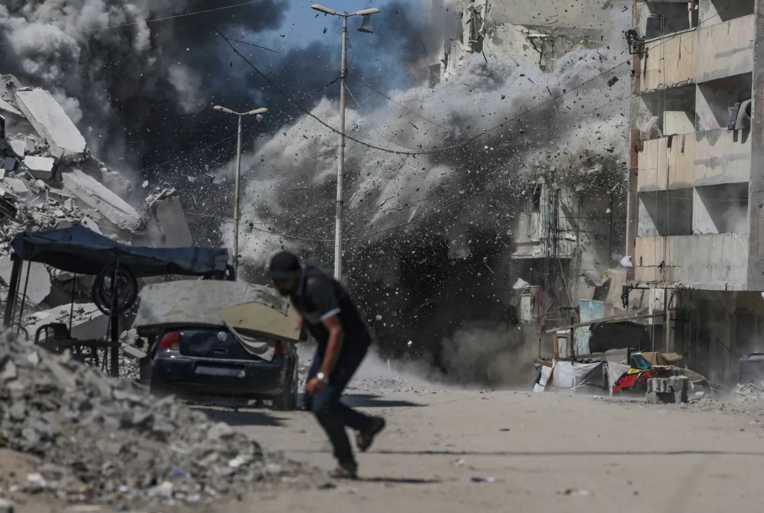 فلسطيني يهرع لاتخاذ ساتر في أثناء القصف الجوي إسرائيلي في مدينة غزة (إ.ب.أ)