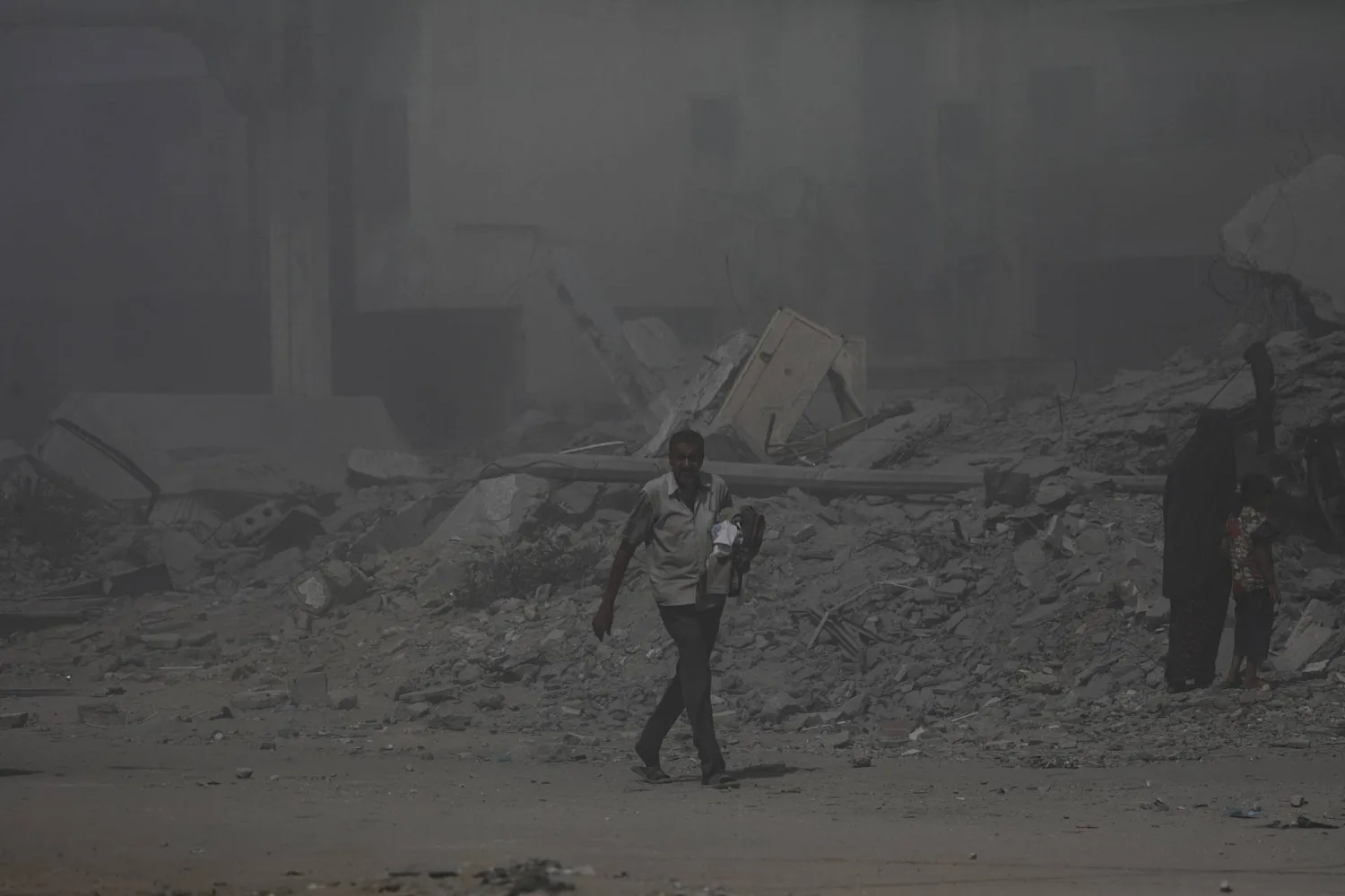 فلسطيني يسير وسط الدخان الكثيف بعد غارة جوية إسرائيلية على مدينة غزة السبت (إ.ب.أ)