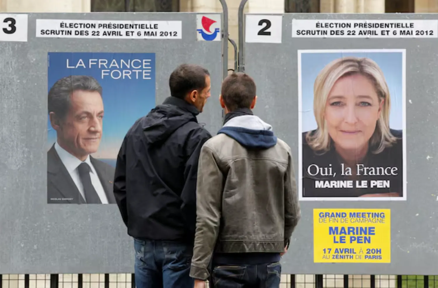 People stop to read the official campaign posters for candidates in the French presidential election: Nicolas Sarkozy, France's President and UMP candidate and Marine Le Pen, France's National Front head in Paris, April 9, 2012. REUTERS/Benoit Tessier/File Photo