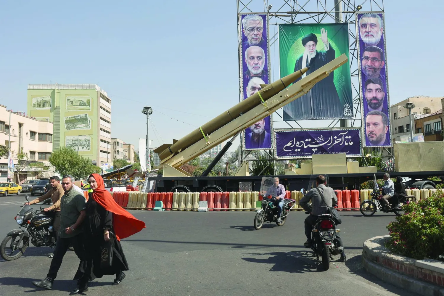 صاروخ إيراني يُعرض بجانب لافتة تحمل صورة المرشد علي خامنئي وقادة من «الحرس الثوري» قُتلوا في هجمات إسرائيلية بأحد شوارع طهران (رويترز)