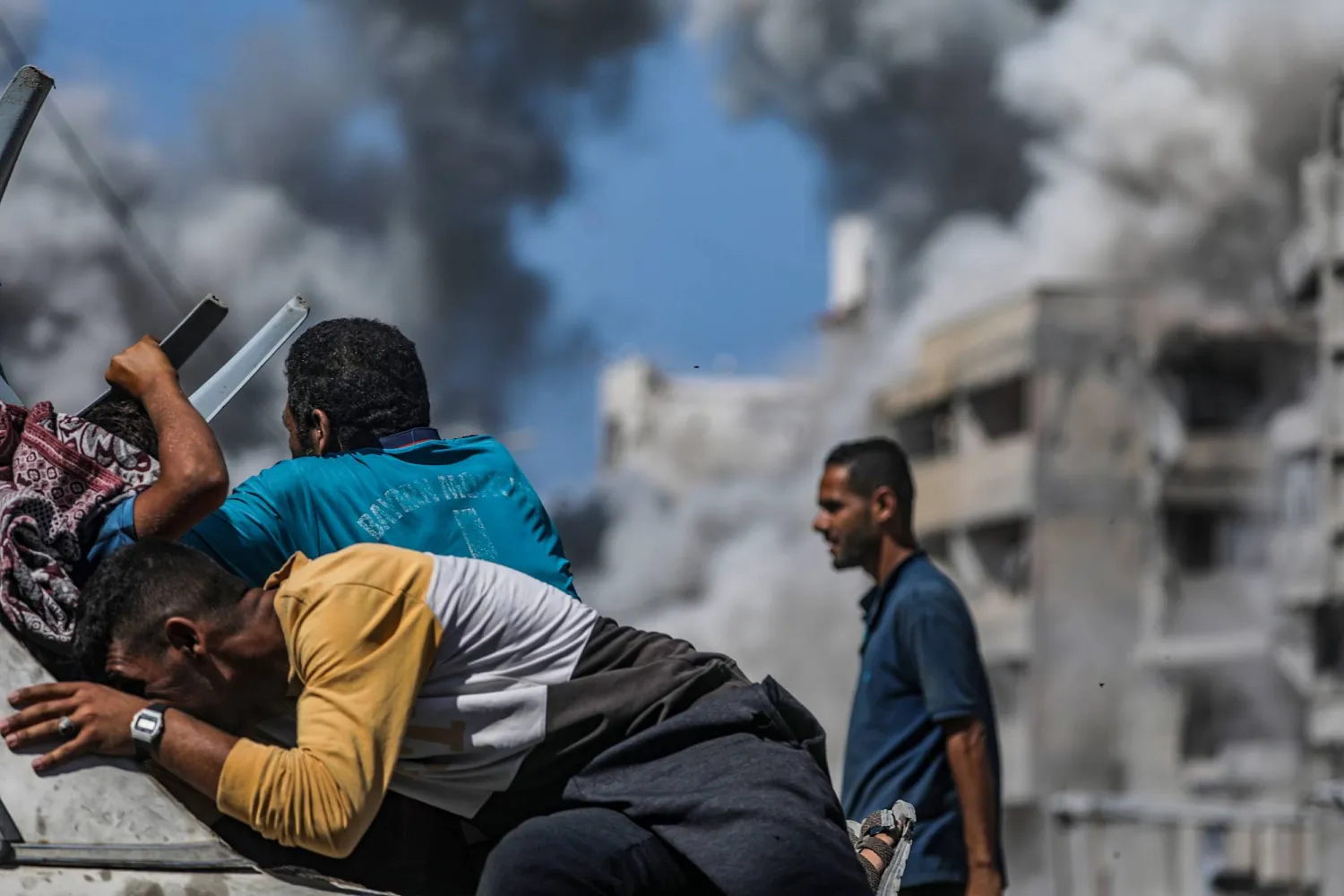 فلسطينيون لحظة وقوع غارة جوية إسرائيلية في مدينة غزة يوم السبت (إ.ب.أ)