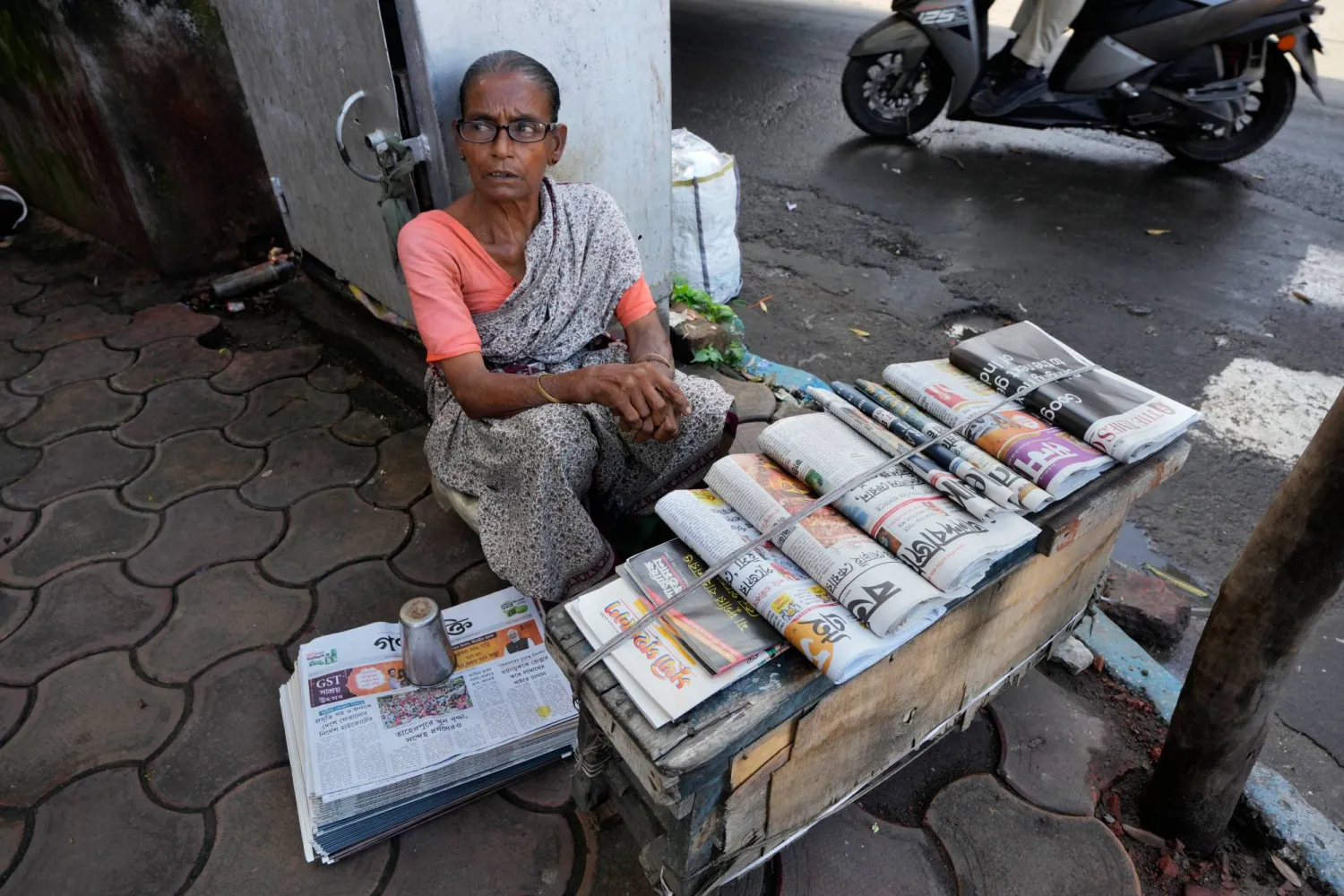 A newspaper vendor waits for customers at her roadside stall in Kolkata, India, Saturday, Sept. 27, 2025. (AP Photo/Bikas Das)
