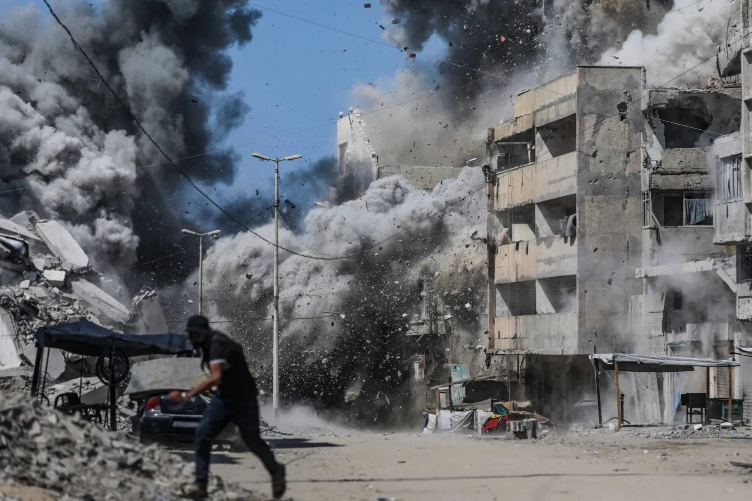 فلسطيني يحاول الاحتماء خلال غارة إسرائيلية على مدينة غزة، أمس (إ.ب.أ)