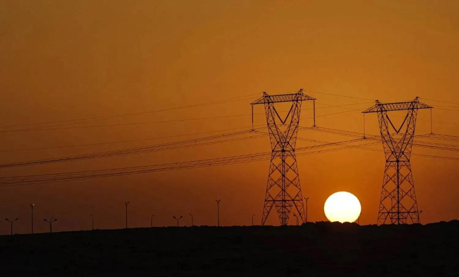 غروب الشمس بين أبراج الضغط العالي للكهرباء (رويترز)