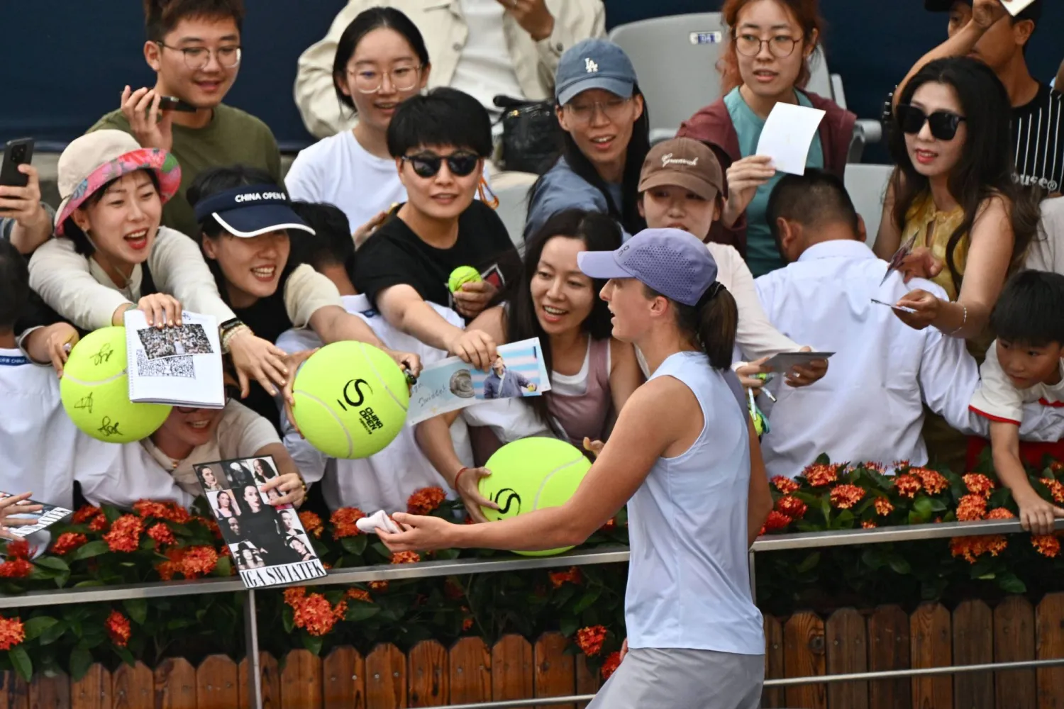 Poland's Iga Swiatek signs autographs for fans after her women's singles match against Colombia's Camila Osorio at the China Open tennis tournament in Beijing on September 29, 2025. (Photo by Pedro Pardo / AFP)