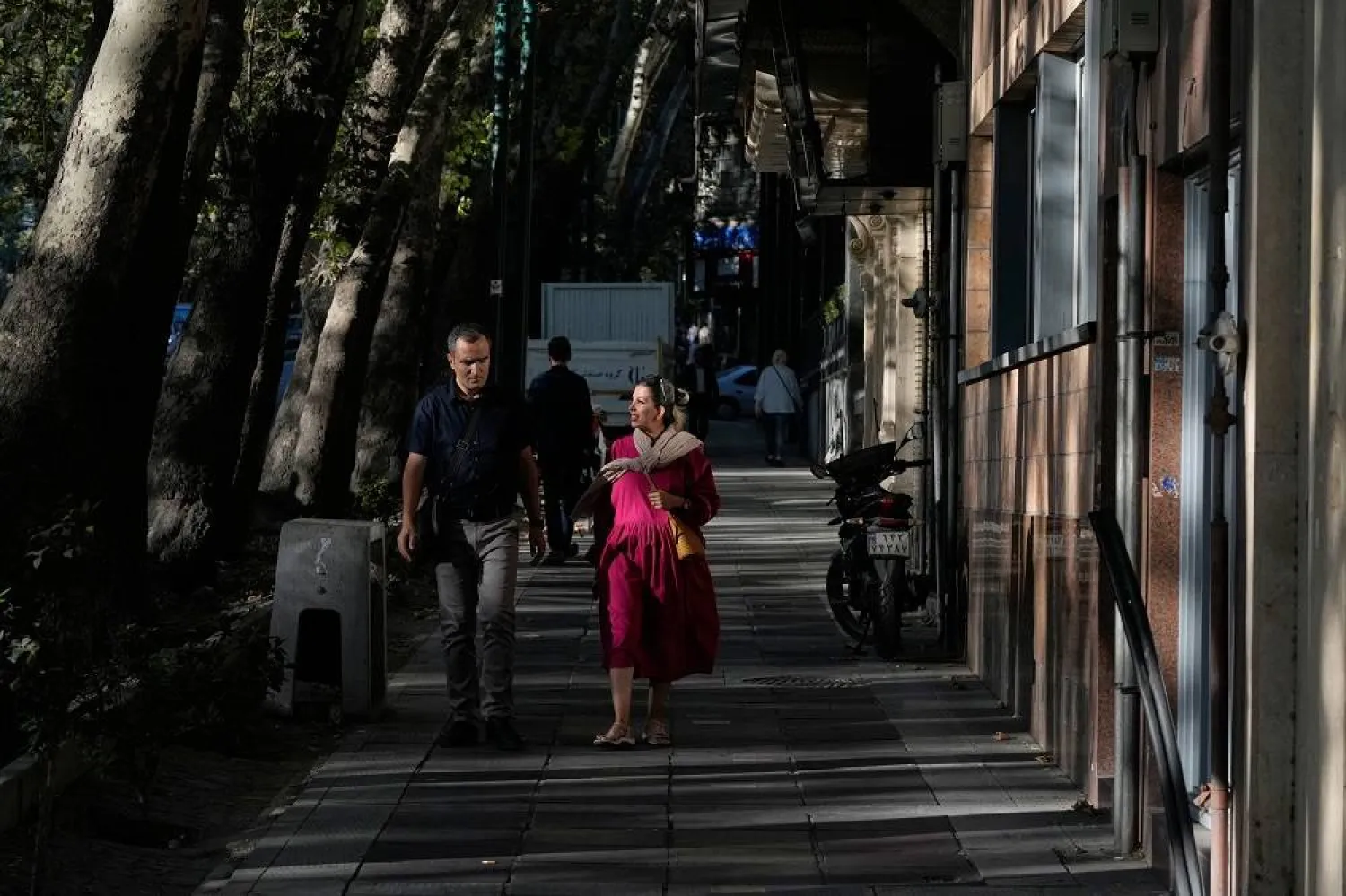 People walk on a sidewalk in northern Tehran, Iran, Sunday, Sept. 28, 2025. (AP)