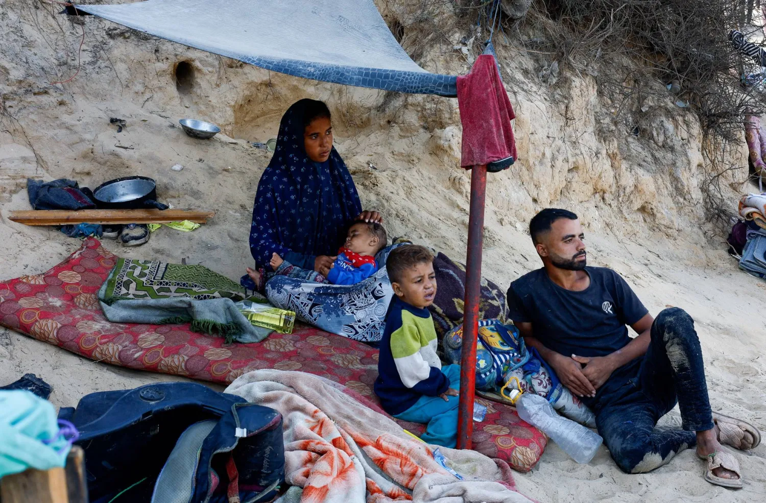 أسرة فلسطينية غادرت شمال قطاع غزة بسبب العمليات الإسرائيلية تجلس في ملجأ مؤقت (رويترز) 