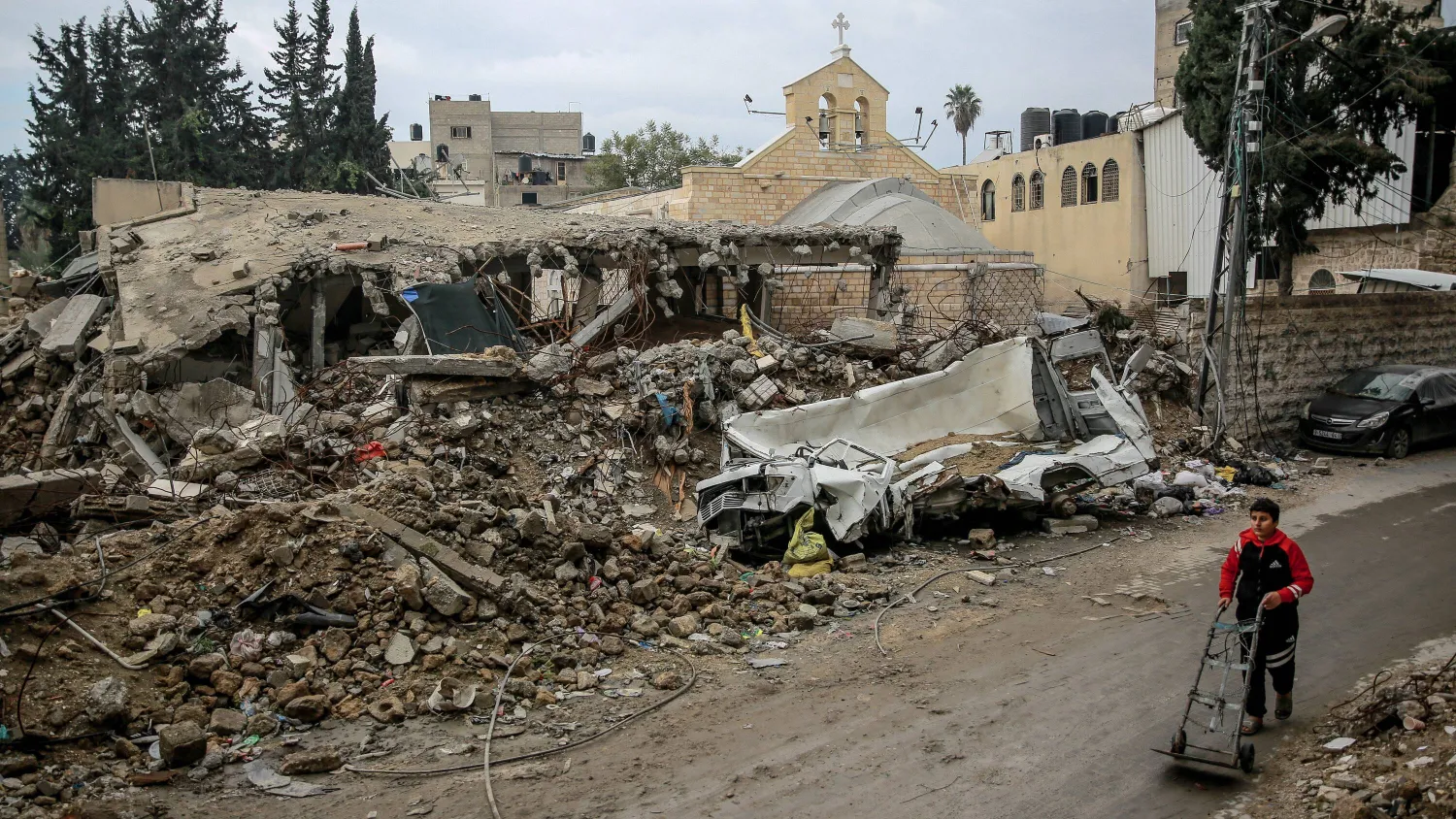 طفل يمشي أمام كنيسة القديس بورفيريوس للروم الأرثوذكس في غزة والتي تضررت خلال القصف الإسرائيلي (أ.ف.ب)