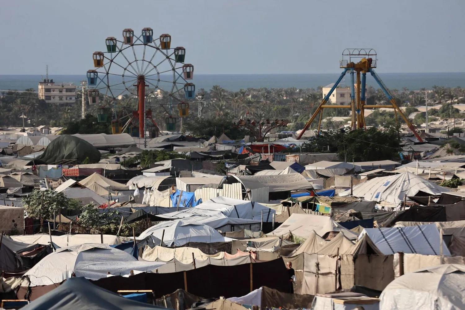 An idle Ferris wheel stands near tents at a camp for displaced people in Khan Yunis in the southern Gaza Strip, on September 29, 2025, amid the ongoing conflict between Israel and the Palestinian militant group Hamas. (Photo by Omar AL-QATTAA / AFP)