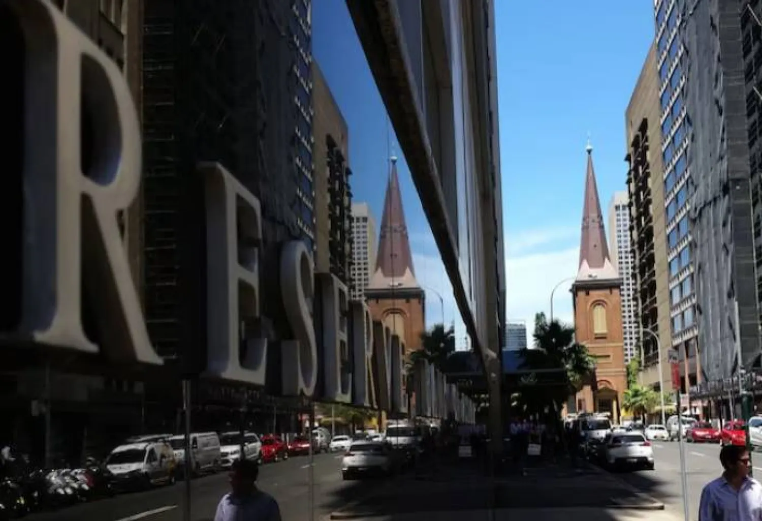 مشاة يمرون أمام مبنى بنك الاحتياطي الأسترالي وسط سيدني (رويترز)