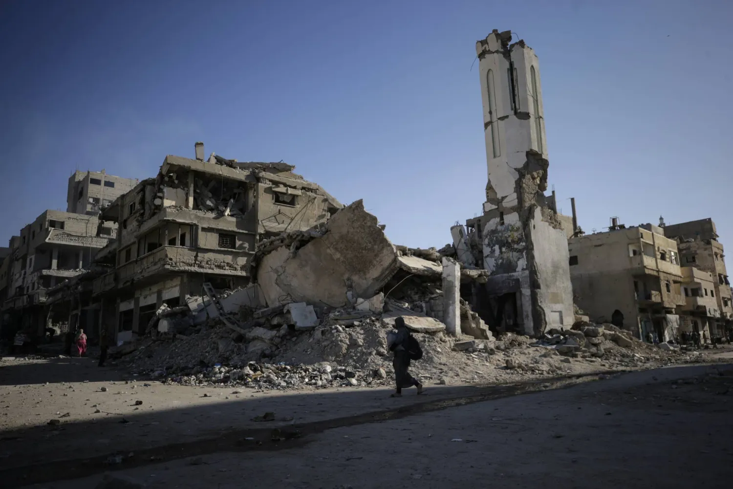 امرأة فلسطينية تمشي بجوار أبنية دُمرت جراء غارة جوية إسرائيلية في مدينة غزة يوم 30 سبتمبر 2025 (إ.ب.أ) 