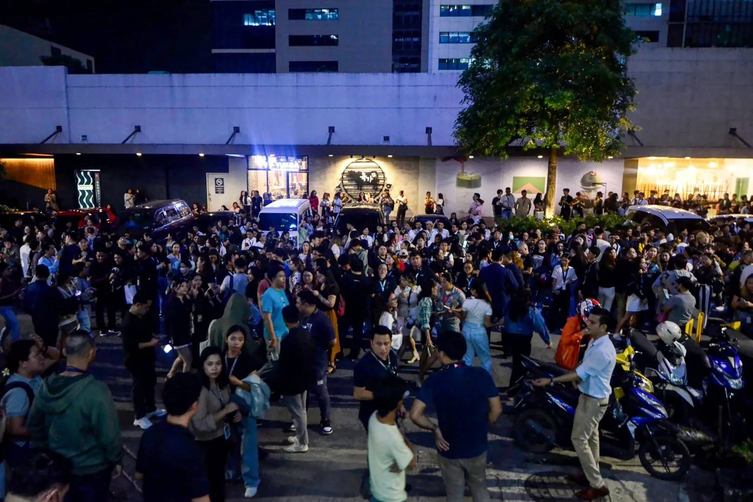 يستخدم موظفو مركز الاتصالات هواتفهم المحمولة أثناء تجمعهم خارج مبنى مكتبهم بعد وقوع زلزال في سيبو في وسط الفلبين يوم 30 سبتمبر 2025 (أ.ف.ب) 