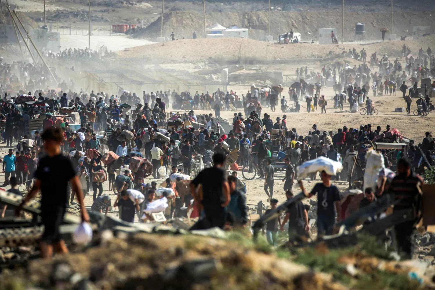 فلسطيونيون يسيرون حاملين مساعدات إنسانية تلقوها من مركز تديره ”مؤسسة غزة الإنسانية“ المدعومة من أميركا وإسرائيل في النصيرات وسط قطاع غزة أمس (أ.ف.ب)
