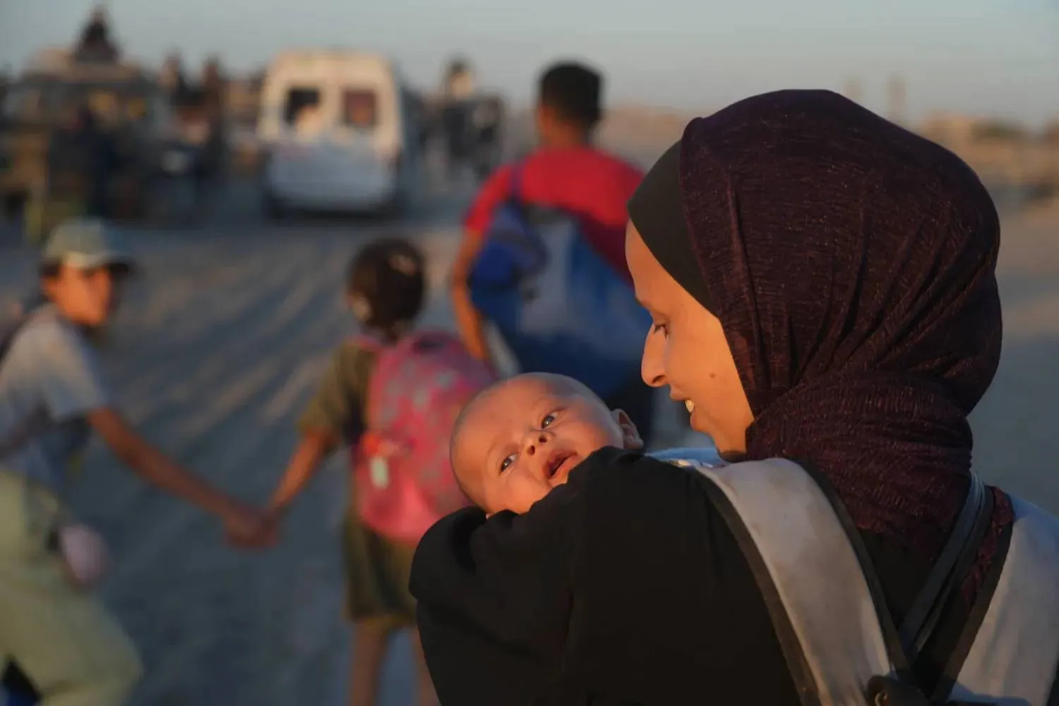  Gazze şehrine dönüş yolculuğu sırasında kucağında çocuğunu taşıyan Filistinli bir kadın (AP)
